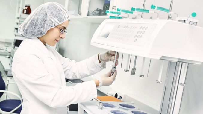 Pharmaceutical scientific female researcher in protective uniform working with dissolution tester at pharmacy industry manufacture factory laboratory Process analytical technology