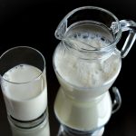 milk in a glass and jug against a black background. The source of casein and casomorphin for purification.