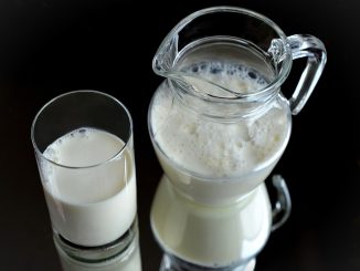 milk in a glass and jug against a black background. The source of casein for purification.