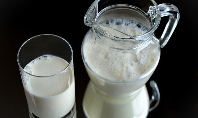 milk in a glass and jug against a black background. The source of casein for purification.