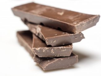 Chunks of dark chocolate piled up on a white background. An example of confectionary.