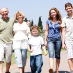 Ant-aging ingredients should be used by all, whatever their age. Family walking arm in arm along a road towards the camera and of all ages.