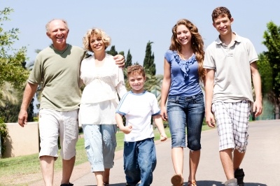 Ant-aging ingredients should be used by all, whatever their age. Family walking arm in arm along a road towards the camera and of all ages.