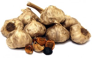 Black garlic cloves and bulbs on a white background.