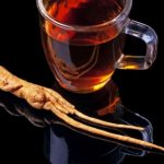 Ginseng tea on a black background with a root of ginseng.