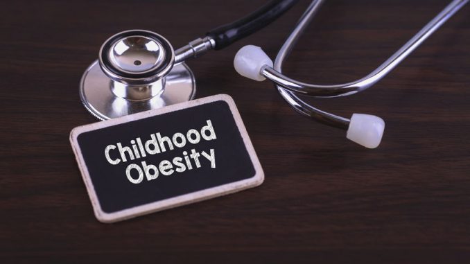Medical concept- childhood obesity words written on label tag with stethoscope on wood background