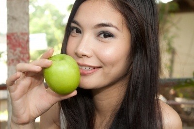 Beautiful girl about to chomp on a green apple.