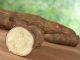 Raw cassava (lat. manihot esculenta) on wood with green background (selective focus, focus on the front)