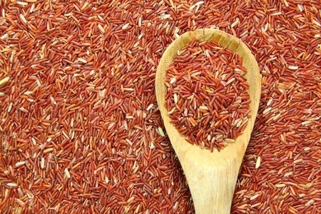 Red yeast rice, some in a wooden spoon, full picture.