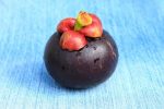 A mangosteen fruit on a light blue table.
