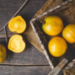 Lucuma fruits, some cut in half and sitting in a basket.