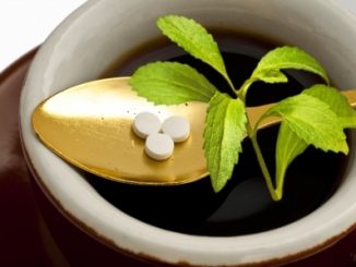 Stevia pills and stevia plant on a golden spoon in a bowl.