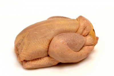An uncooked chicken on a white background.