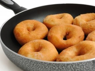 Ring doughnuts in a black frying pan.
