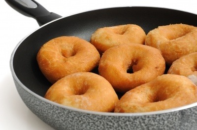 Ring doughnuts in a black frying pan.