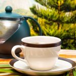 A cup of tea with a stylish half shot of a kettle.