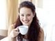 Beautiful girl, smiling, looking face on, holding a white cup of coffee