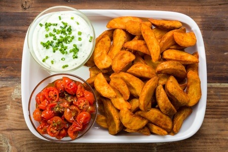 Potato wedges with dip and roasted tomatoes and fresh chives. A potential source of acrylamide.