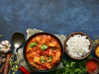 Chicken tikka masala - traditional dish of indian cuisine in a clay bowl over dark blue slate, stone or concrete background.Top view with copy space.