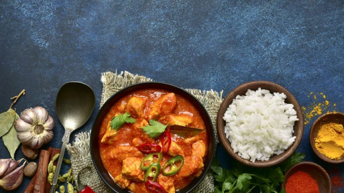 Chicken tikka masala - traditional dish of indian cuisine in a clay bowl over dark blue slate, stone or concrete background.Top view with copy space.