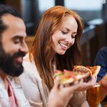 Smiling friends eating pizza and drinking beer at restaurant or pub