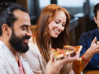 Smiling friends eating pizza and drinking beer at restaurant or pub