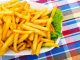 French fries with lettuce on a white plate, on a plaid tablecloth.. One of the foods associated with acrylamide formation.