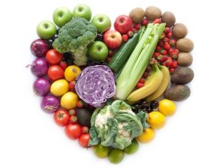 A mix of fruit and vegetables arranged into a heart shape on a white background.