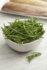 72866136 - fresh raw green samphire in a bowl with fresh fish in the background