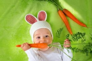 Baby in rabbit hat eating fresh carrot. Copyright: candy18 / 123RF Stock Photo