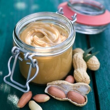 Fresh peanut butter in a jar with lid. Peanuts with nuts.