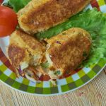 A Glamorgan sausage served with lettuce and a tomato on a check plate on a wooden table.