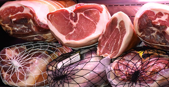 Cured hams cut in half with net covering. Some produced with nitrate and nitrite preservation