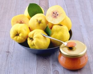 Quince fruit in a bowl with a jar of membrillo. 