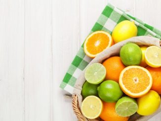 Various citrus fruit in a basket on a white table.