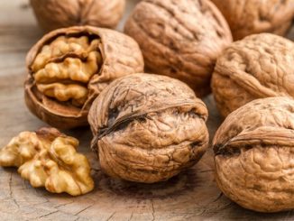 Whole walnuts with some broken to expose the kernel.