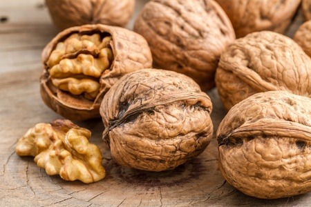 Whole walnuts with some broken to expose the kernel.