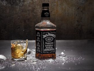 Jack Daniels bourbon/American Whiskey in a bottle and glass against a dark background.