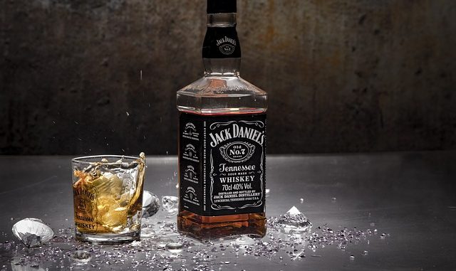Jack Daniels bourbon/American Whiskey in a bottle and glass against a dark background.