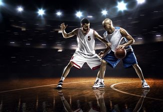 Two basketball players in action in gym in lights