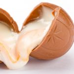 Creme eggs: A broken creme egg with the fondant icing oozing out of both ends. All on a white background.