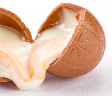 Creme eggs: A broken creme egg with the fondant icing oozing out of both ends. All on a white background.