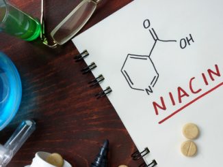 Notepad with chemical formula of niacin (vitamin B3) on the wooden table.