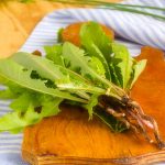 Dandelion root and leaves on a wooden board