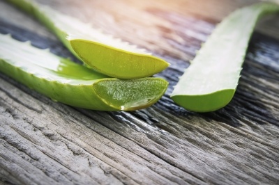 Cut halves of aloe leaves on a wooden table.
