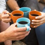 A group of friends making a toast with coffee.
