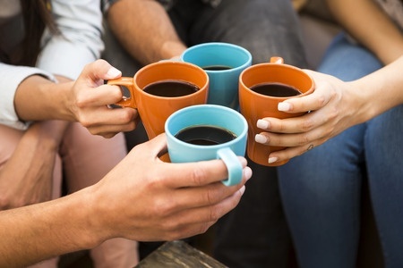 A group of friends making a toast with coffee.