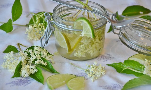 A tisane of elderflower, leaves with glass on a white cloth.