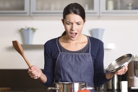 A young woman looking at the tragedy unfurled in her cooking pan.