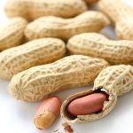 Peanuts, some cracked on a white background.